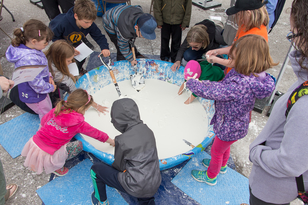 Group of people playing in a plastic pool filled with oobleck